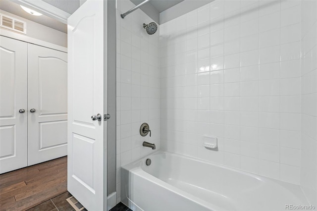 full bathroom with visible vents, wood finished floors, and washtub / shower combination