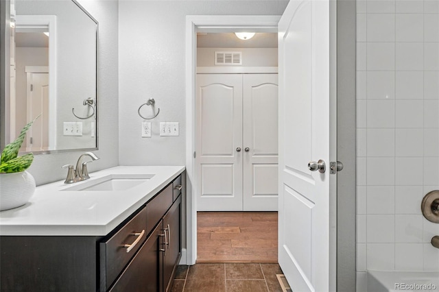 full bathroom featuring vanity, visible vents, and wood finished floors
