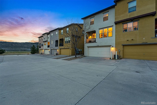 view of front of home with an attached garage, central air condition unit, concrete driveway, and stucco siding