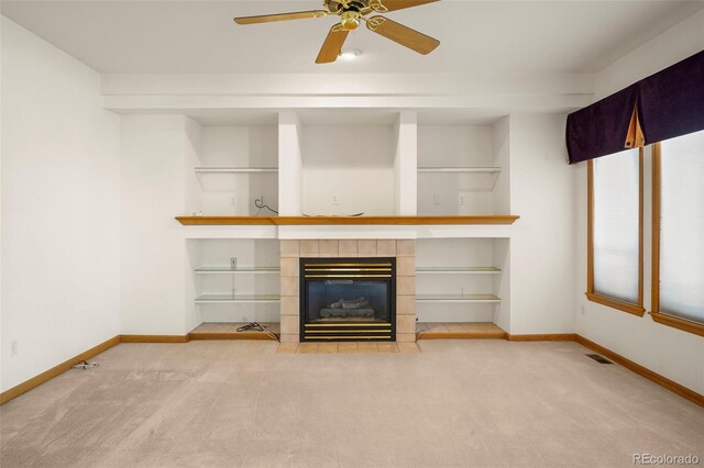 unfurnished living room featuring ceiling fan, carpet floors, and a tile fireplace