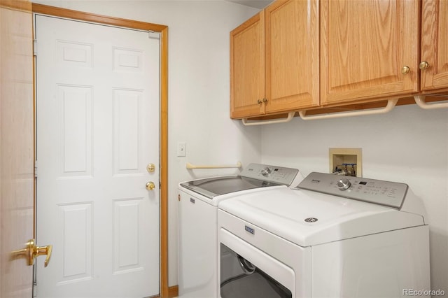 clothes washing area featuring washer and clothes dryer and cabinets