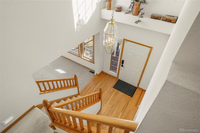 foyer with a towering ceiling, wood-type flooring, and a chandelier