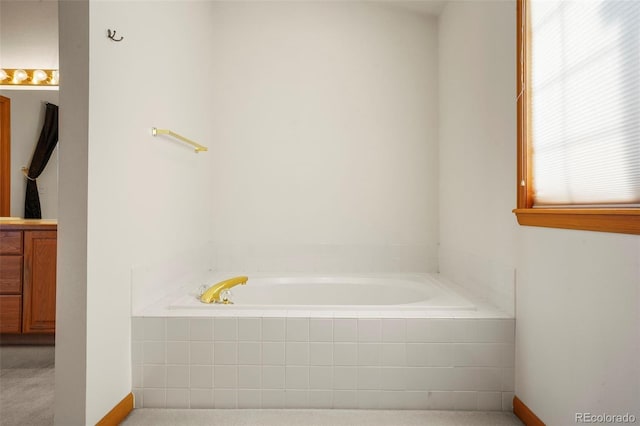 bathroom featuring vanity and tiled bath