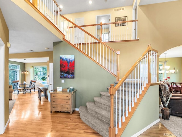 3648 Heatherwood Way, Evergreen, CO 80439 - stairway featuring a chandelier, wood finished floors, a high ceiling, arched walkways, and recessed lighting