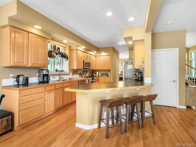 3648 Heatherwood Way, Evergreen, CO 80439 - kitchen featuring stainless steel appliances, light brown cabinetry, light wood-style flooring, a kitchen breakfast bar, and recessed lighting