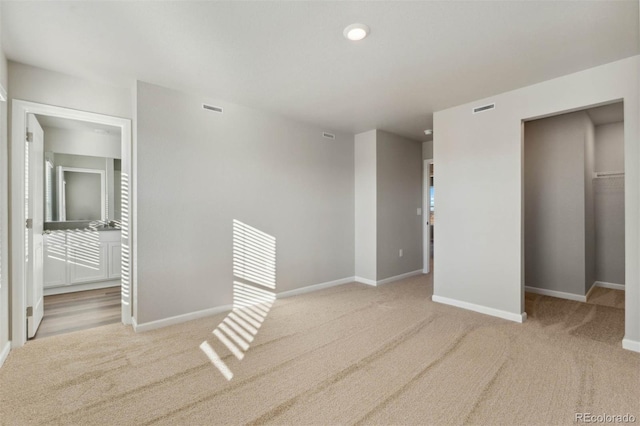 interior space with a walk in closet, baseboards, visible vents, and carpet floors