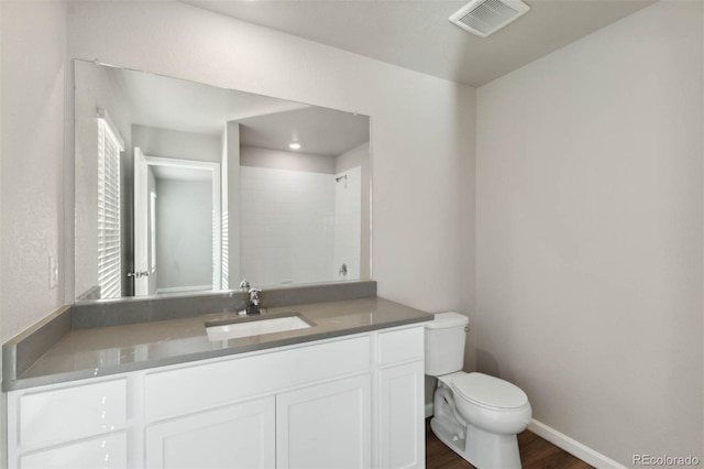 bathroom with visible vents, toilet, wood finished floors, baseboards, and vanity