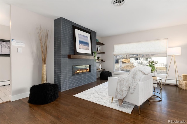 living room featuring a tile fireplace, dark hardwood / wood-style flooring, and baseboard heating