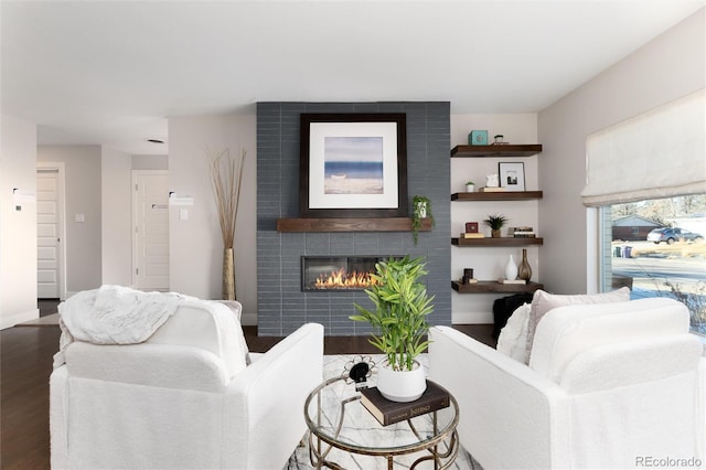 living room with a tile fireplace and dark hardwood / wood-style flooring