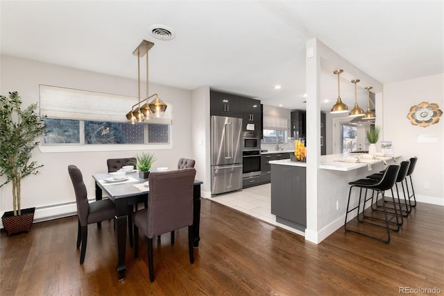 dining space featuring sink, baseboard heating, and dark wood-type flooring