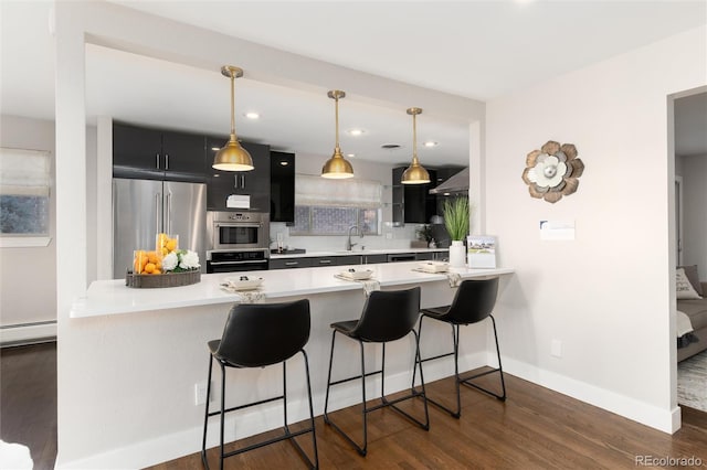 kitchen featuring decorative light fixtures, wall chimney range hood, high end fridge, and kitchen peninsula