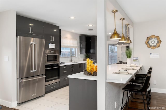 kitchen featuring stainless steel appliances, hanging light fixtures, kitchen peninsula, a kitchen bar, and backsplash