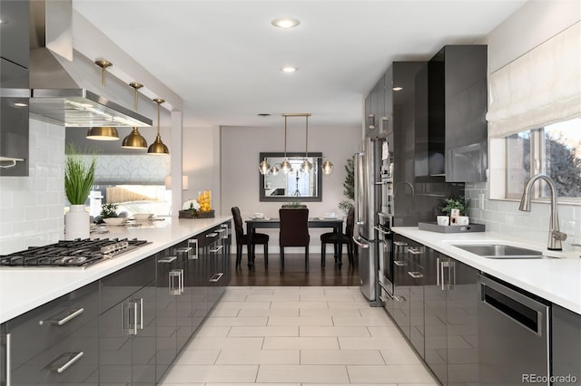 kitchen with appliances with stainless steel finishes, hanging light fixtures, tasteful backsplash, and sink