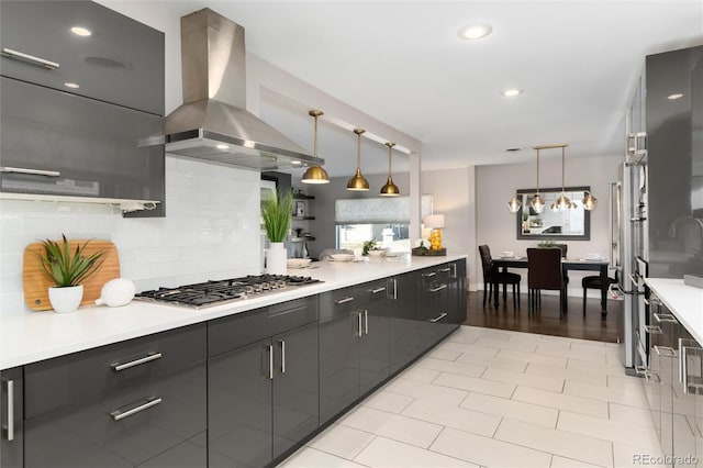 kitchen featuring backsplash, island range hood, stainless steel gas stovetop, and pendant lighting