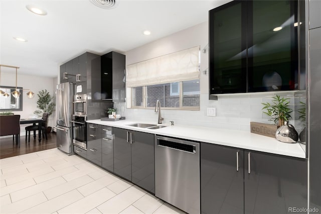 kitchen featuring appliances with stainless steel finishes, pendant lighting, tasteful backsplash, and sink