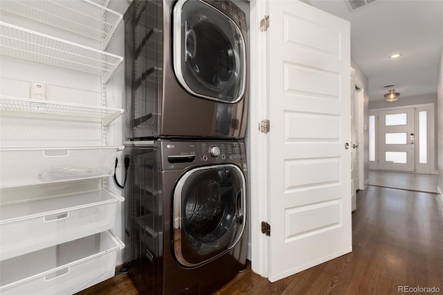 clothes washing area with dark wood-type flooring and stacked washing maching and dryer