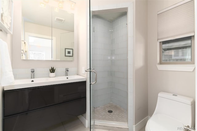 bathroom with toilet, vanity, and a shower with shower door