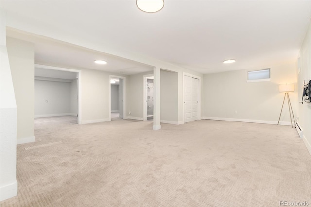 basement with baseboard heating and light colored carpet