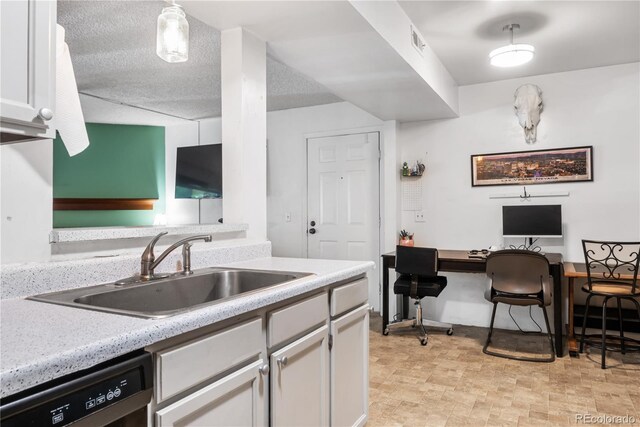 kitchen with pendant lighting, dishwasher, sink, white cabinets, and a textured ceiling