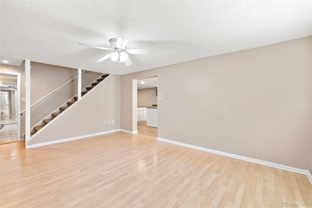 6150 Reed St, Arvada, CO 80003 - spare room with light wood finished floors, stairway, baseboards, a ceiling fan, and a textured ceiling