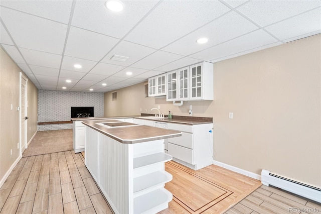 6150 Reed St, Arvada, CO 80003 - kitchen with a baseboard radiator, open shelves, baseboards, light wood-type flooring, and a paneled ceiling
