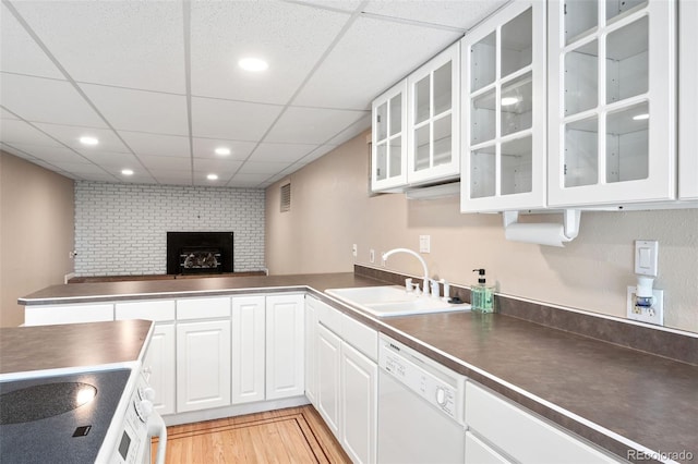 6150 Reed St, Arvada, CO 80003 - kitchen featuring white appliances, a sink, a brick fireplace, dark countertops, and white cabinetry
