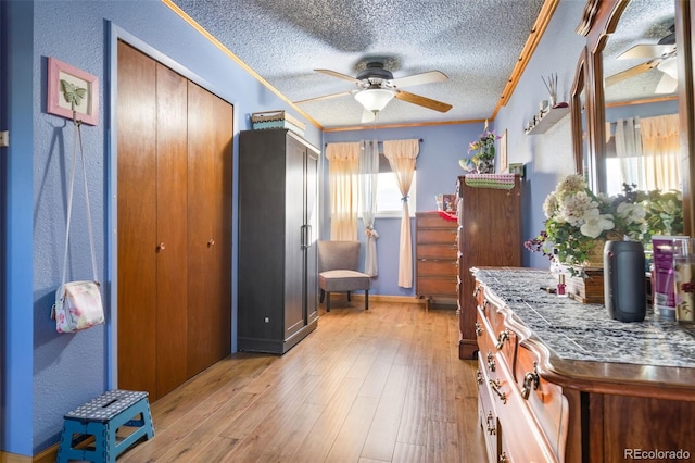 bedroom featuring crown molding, a textured ceiling, and light wood finished floors