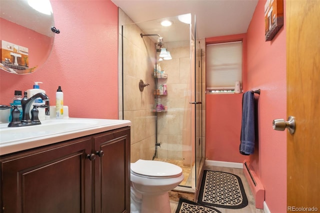 full bathroom featuring vanity, baseboard heating, a shower stall, and toilet