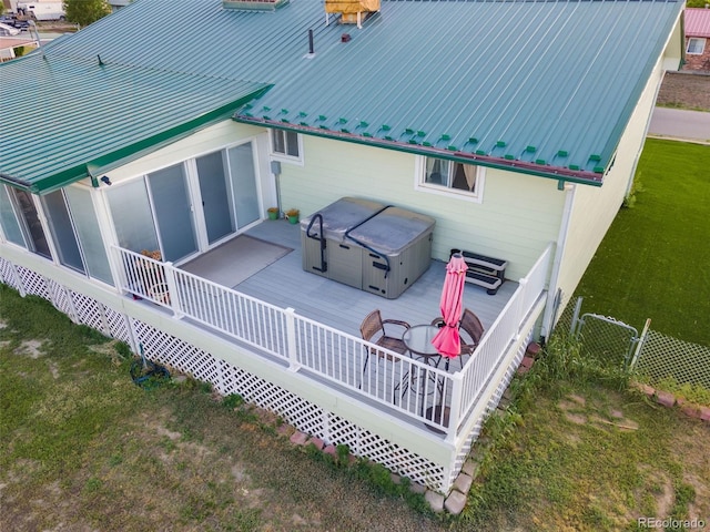 rear view of property featuring a hot tub, metal roof, a lawn, and a wooden deck