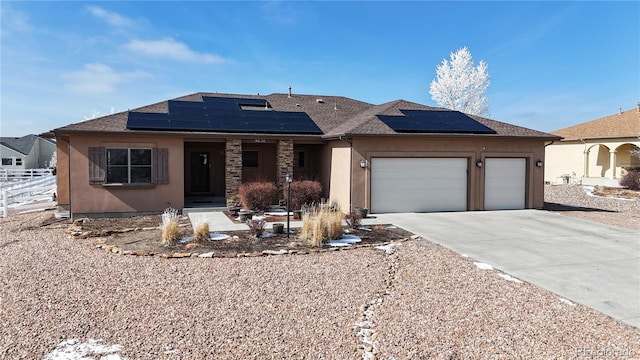 ranch-style home featuring a garage, stucco siding, driveway, and solar panels