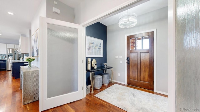 foyer with dark wood-type flooring, recessed lighting, a chandelier, and baseboards