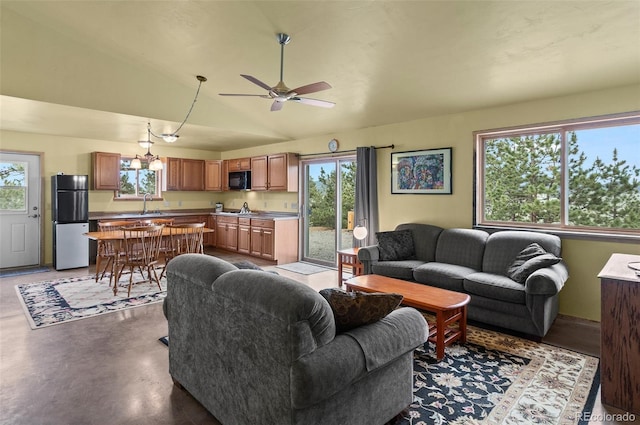 living room with ceiling fan with notable chandelier, vaulted ceiling, and sink