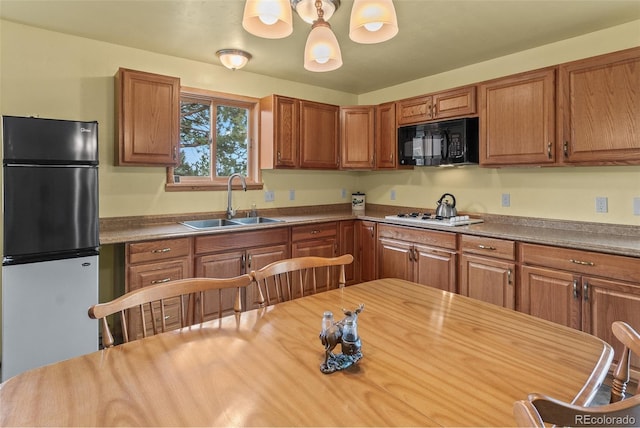 kitchen with pendant lighting, butcher block counters, sink, and stainless steel refrigerator