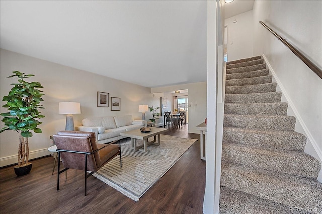 living area with dark wood-style floors, stairs, and baseboards