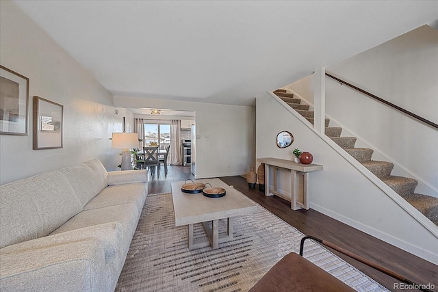 living area featuring wood finished floors, stairs, baseboards, and vaulted ceiling