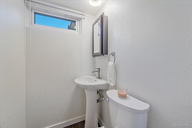 bathroom with a textured wall, wood finished floors, and toilet