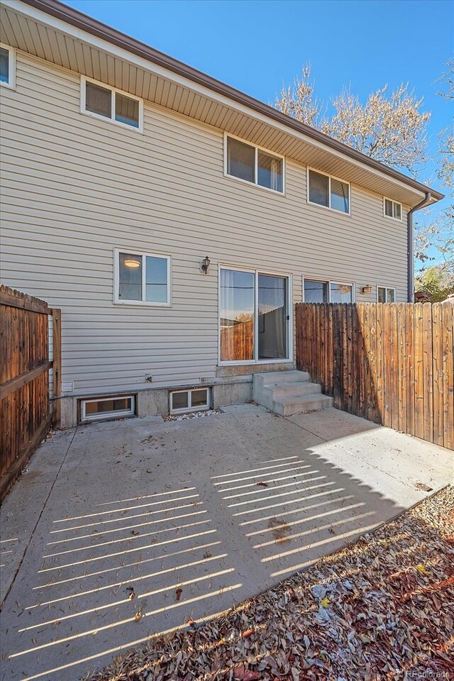 back of property with fence, a patio, and entry steps