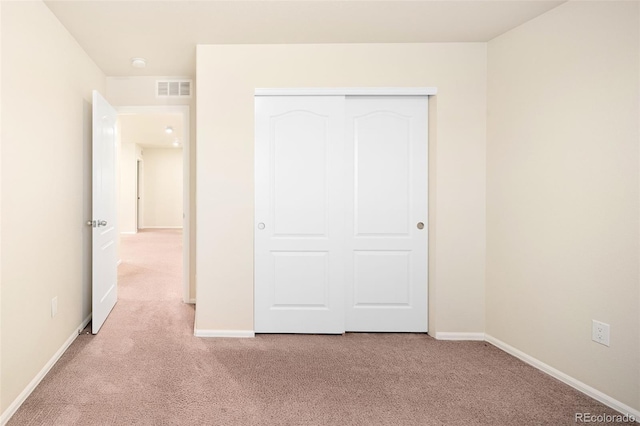 unfurnished bedroom with a closet and light colored carpet