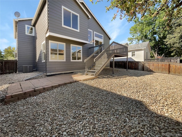 rear view of property featuring central AC, a wooden deck, and a patio area