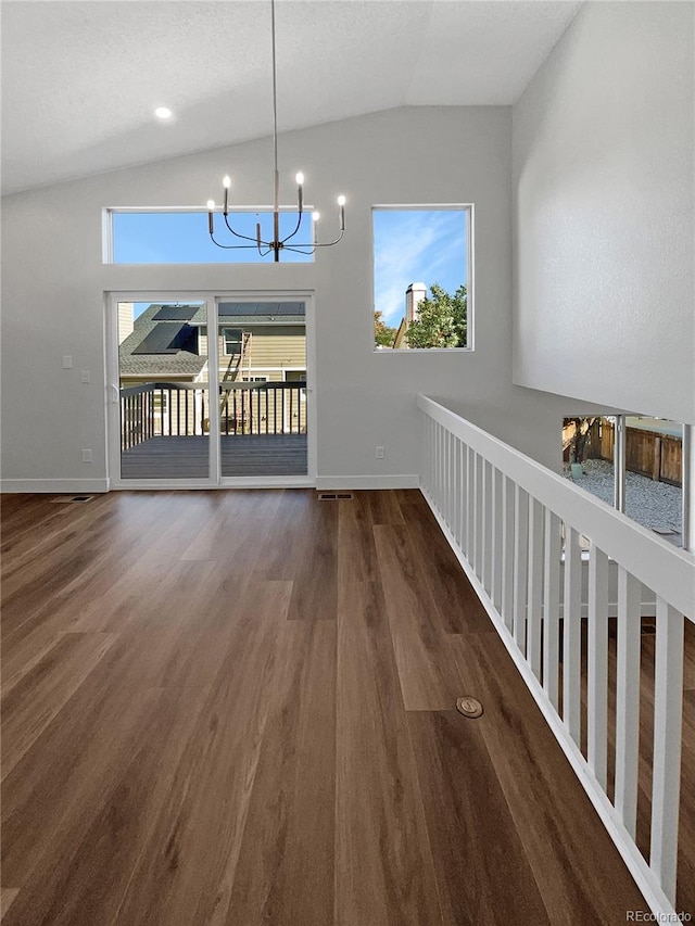 unfurnished dining area with vaulted ceiling, a chandelier, and dark wood-type flooring