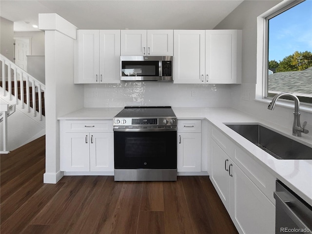 kitchen with white cabinets, stainless steel appliances, sink, and dark hardwood / wood-style flooring