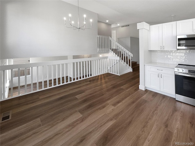 kitchen featuring appliances with stainless steel finishes, dark wood-type flooring, tasteful backsplash, and white cabinetry