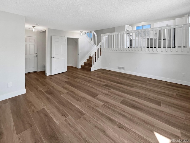 unfurnished room with a textured ceiling and dark hardwood / wood-style floors