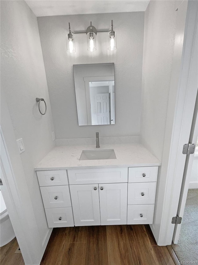 bathroom with wood-type flooring, vanity, and toilet