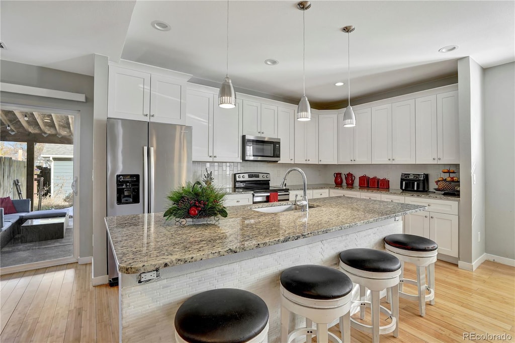 kitchen with light hardwood / wood-style flooring, stainless steel appliances, white cabinetry, and sink