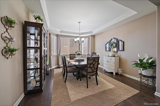 dining area featuring a chandelier, a raised ceiling, baseboards, and dark wood finished floors