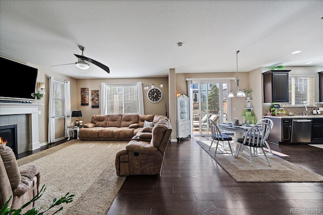 living area featuring a fireplace, a textured ceiling, dark wood-type flooring, and baseboards