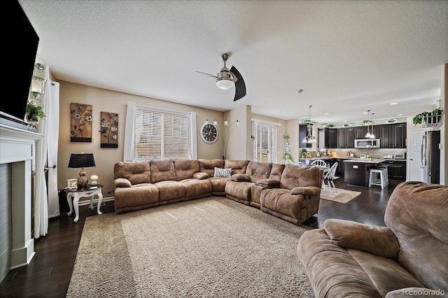 living room with a ceiling fan, recessed lighting, a fireplace, dark wood-style flooring, and a textured ceiling