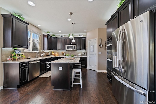 kitchen featuring tasteful backsplash, a kitchen island, appliances with stainless steel finishes, and dark wood-style flooring