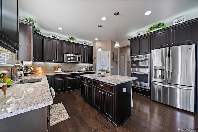 kitchen with tasteful backsplash, a sink, a kitchen island, stainless steel appliances, and dark wood-style flooring